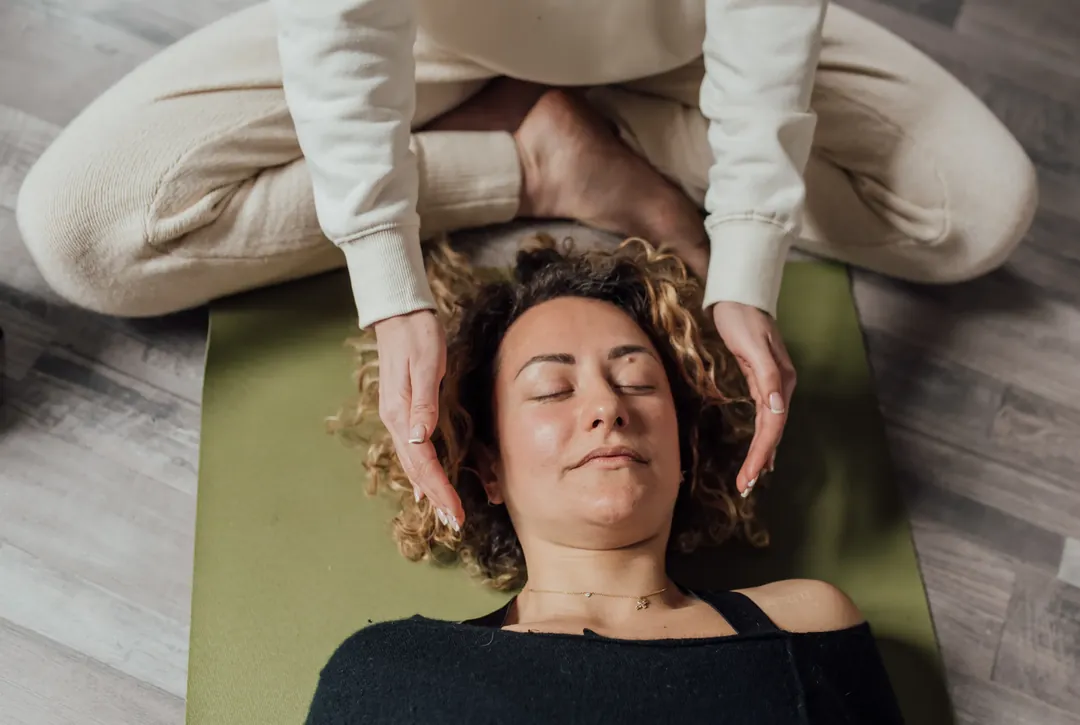 A person resting comfortably during a guided hypnotherapy session while the practitioner supports the process