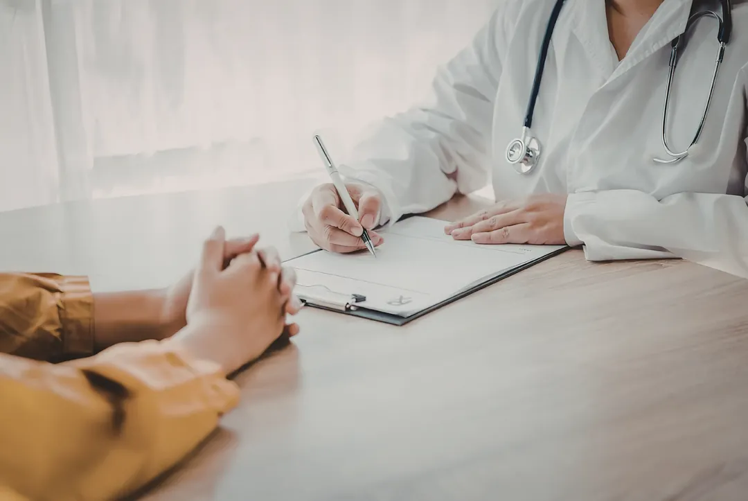 A practitioner taking notes while listening to a client during an initial consultation