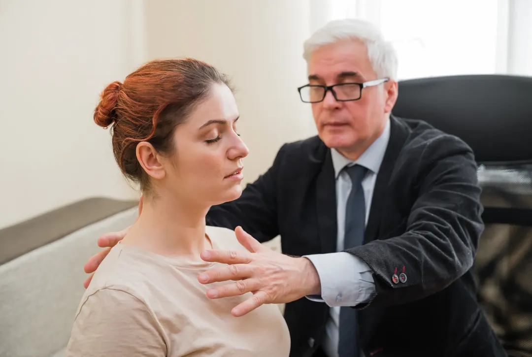 A professional offering supportive, hands-on therapeutic care to a seated client